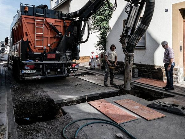 Saugbagger saugt Marteial unter der Straßendecke ab